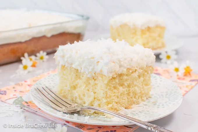A white plate with a piece of frosted cake and a fork on it.