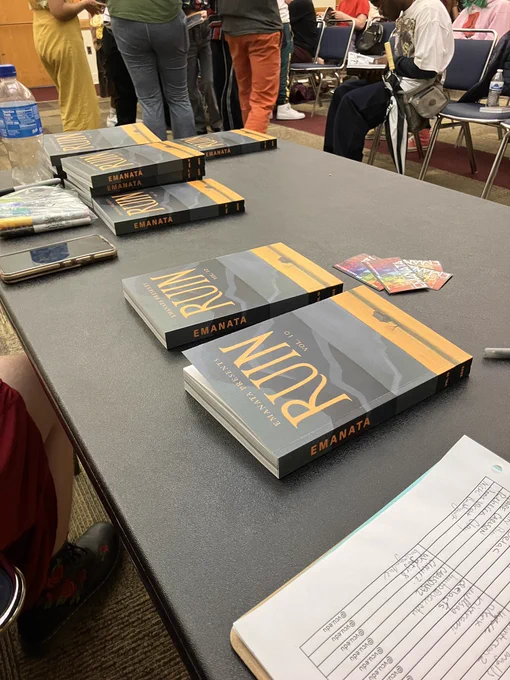 “Ruin” books on a table with a crowd behind them.