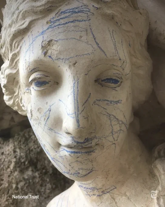 Bright blue marks scrawled across the face of a statue. Photo from National Trust.