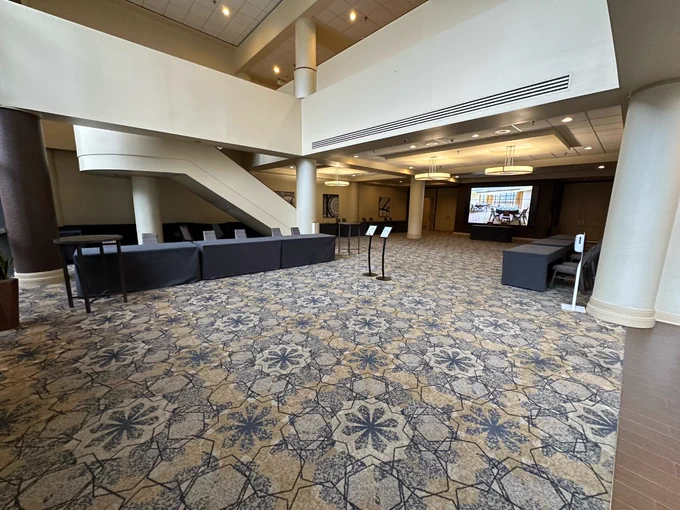 Hotel conference lobby area with registration tables and a stairway behind the tables.