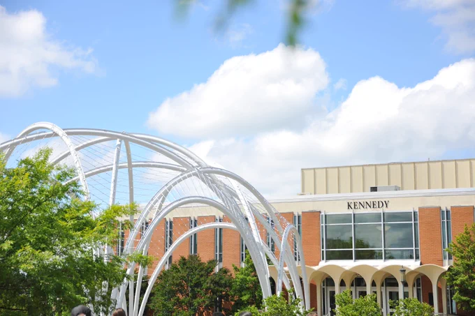 The white arches of the memorial stand tall beside the Kennedy Building.