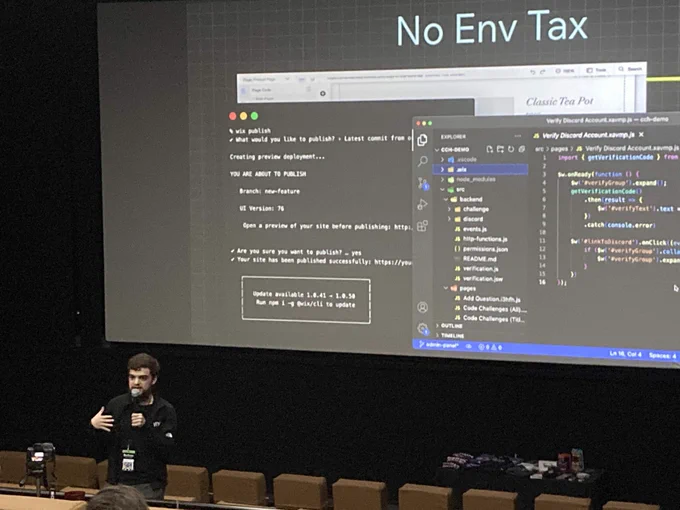 Wix Developer Advocate Thomas Jimenez speaking at HalfStack conference in Charlotte. The large screen behind him says "No Env Tax" with code.