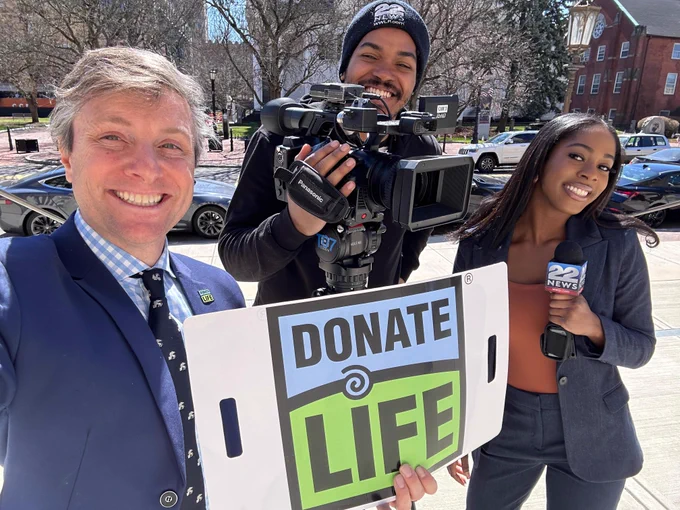 NEDS' Matt Boger holding Donate Life sign with News Crew