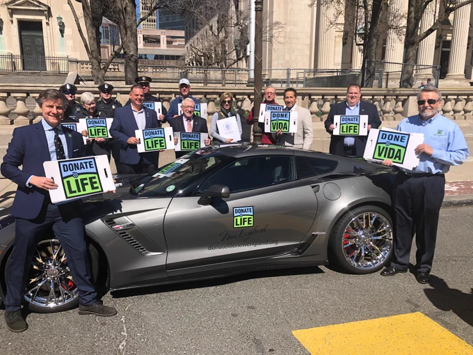 Group at Springfield City Hall holding Donate Life signs in front of Donate Life corvette