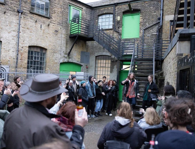 A crowd gathers outside LIMBO for Lizzy's exhibition private view. The team are making a toast for Lizzy and everyone has their drinks raised. 