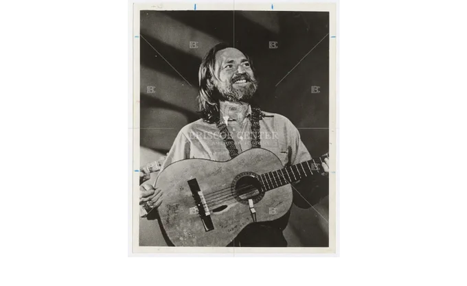 Photo of Willie Nelson holding Trigger, his guitar, while performing at Austin's Soap Creek Saloon. 