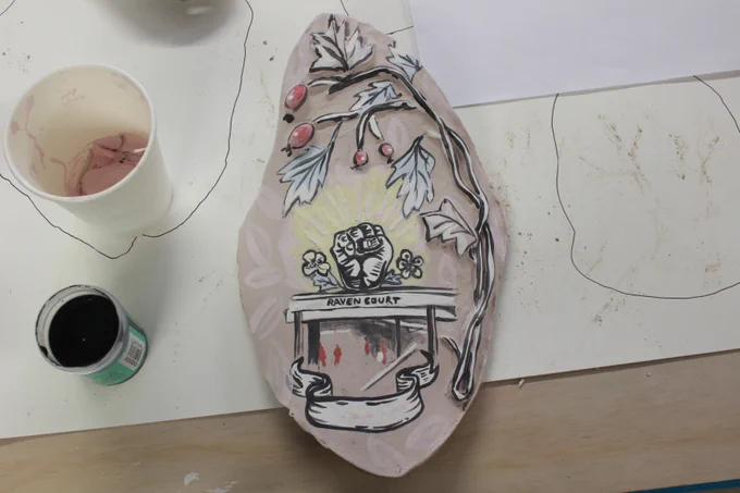 Clay sculpture with a painting of hawthorn berries and a clenched fist