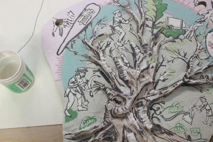 Clay sculpture with a painting of a tree surrounded by people