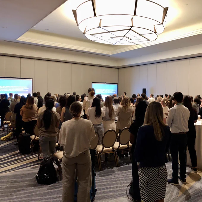 A group of conference attendees standing and applauding.
