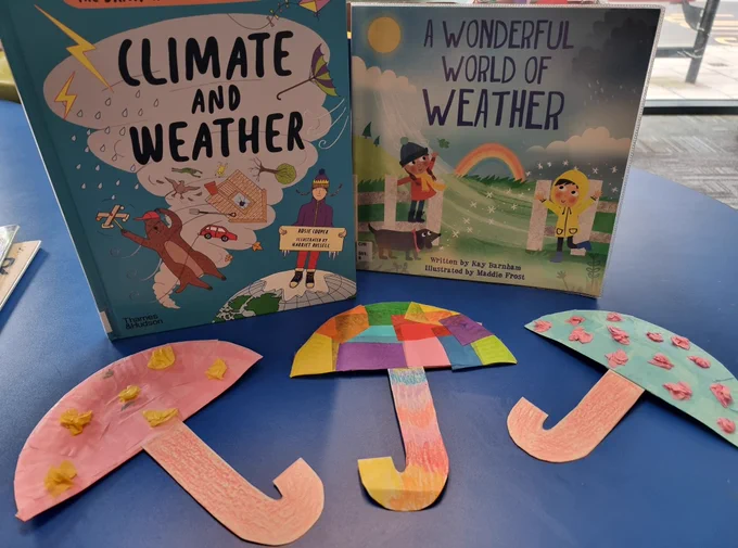 Image shows paper plates in the shape of umbrellas decorated with colourful tissue paper and crayons for the umbrella handles. The books in the background are: left; The Brainiac's Book of the Climate and Weather by Rosie Cooper and illustrated by Harriet Russel, and right; A Wonderful World of Weather by Kay Barnham and illustrated by Maddie Frost. Both books available through Greenwich Libraries.