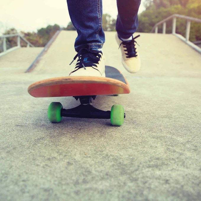 The image shows a shoe on a skateboard with green wheels on a skate ramp.