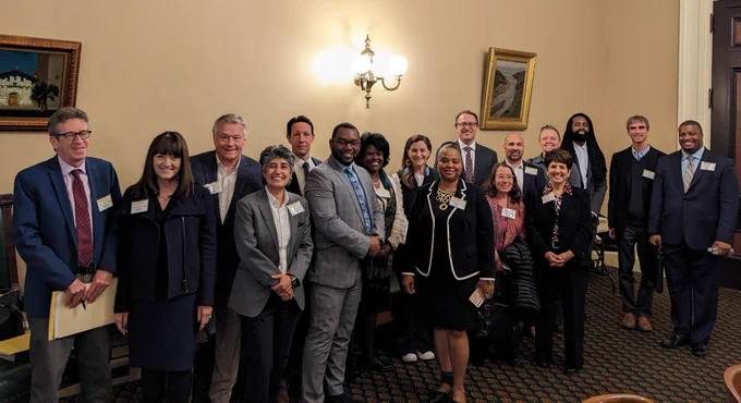 CDFI Day attendees, standing and smiling in a conference room at the California State Capitol, ready to start advocating for CDFI 2023 priorities