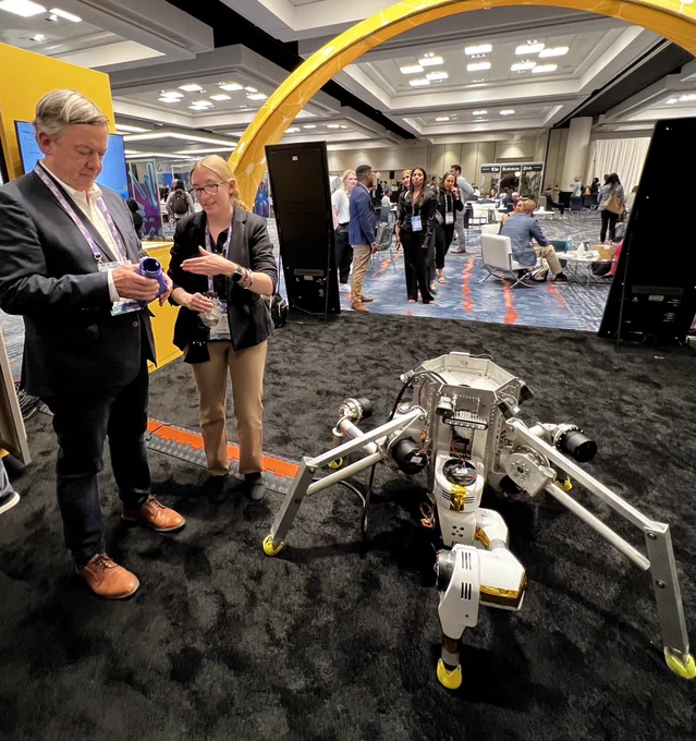 An ASU undergraduate student explains a component of an exploratory robot to a person in an event exhibit hall.