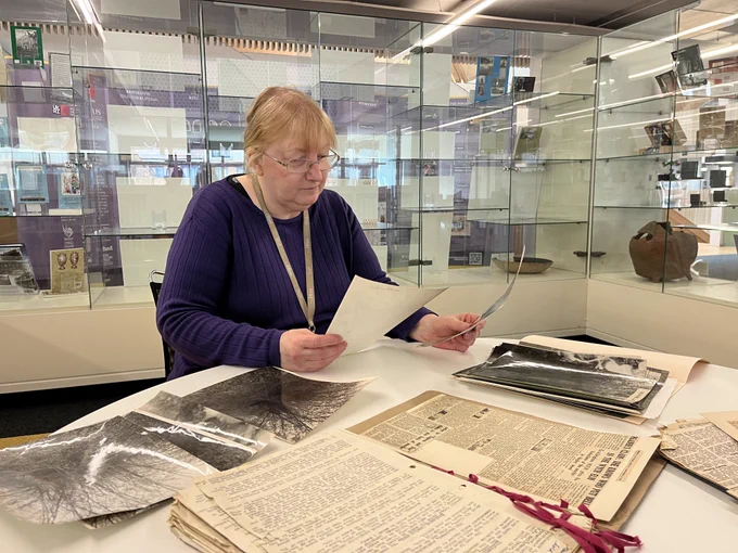 Senior Archivist Maggie Tohill sat with the archives relating to Bella in the Wych Elm