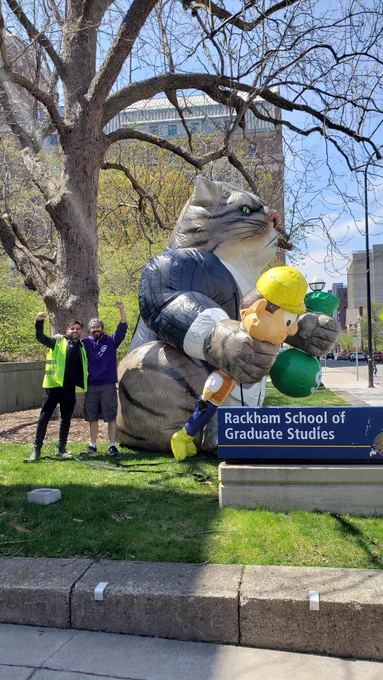 Grads smile as the fat cat is raised outside the rackham grad school 