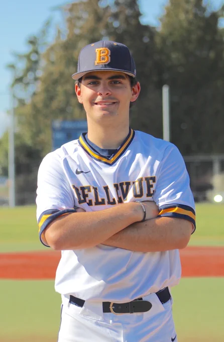 portrait of Graham Ederer, a baseball player, standing with his arms folded, and smiling.
