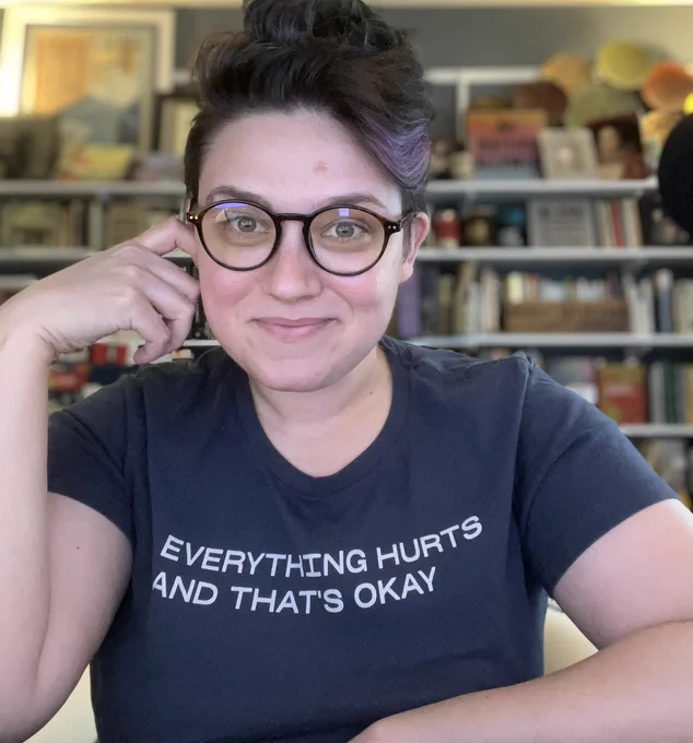 Emily Friedman looks at camera while wearing a T-shirt that reads everything hurts and that’s OK