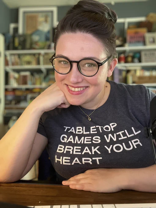 Emily Friedman smiles wearing a shirt that says table top games will break your heart