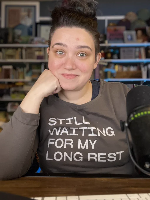 Emily Friedman looks at camera while wearing a sweatshirt that reads still waiting for my long rest