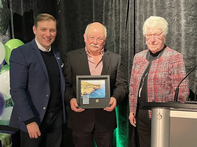 Premier Furey, Fred Thompson, and Mayor Carol McDonald stand together smiling as Fred holds his award. 