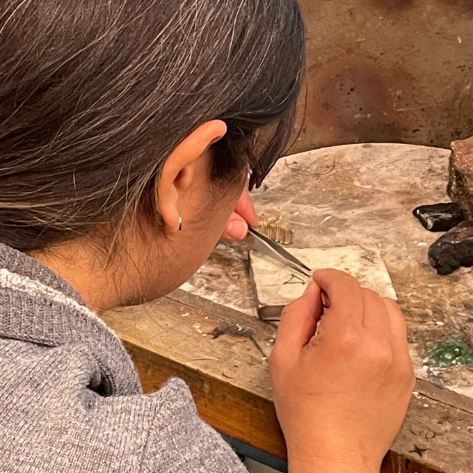 an over the shoulder shot of a pair of hands holding tweezers on a soldering brick.