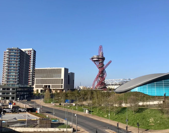 Landscape image of UCL's new UCL East campus to the left with the red ArcelorMittal Orbit tower centre and the London Stadium and Aquatics Centre to the left.
