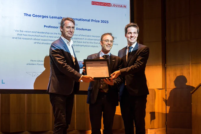 From left to right: Rector of the Catholic University of Louvain, Vincent Blondel, astrophysicist Shep Doeleman, and Belgium's Secretary of State for Recovery and Strategic Investments Thomas Dermine. Together, the three hold a plaque recognizing Doeleman.