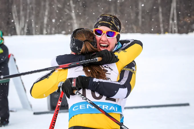 Deedra Irwin and Ulrika Axelsson hug each other while wearing ski gear. Deedra is smiling wide.