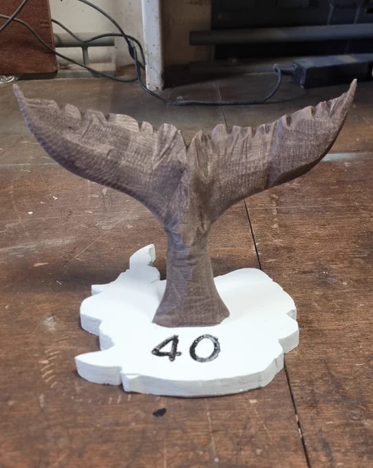 A wooden whale tail mounted on a wooden block in the shape of Antarctic, which has the number 40 carved into it.