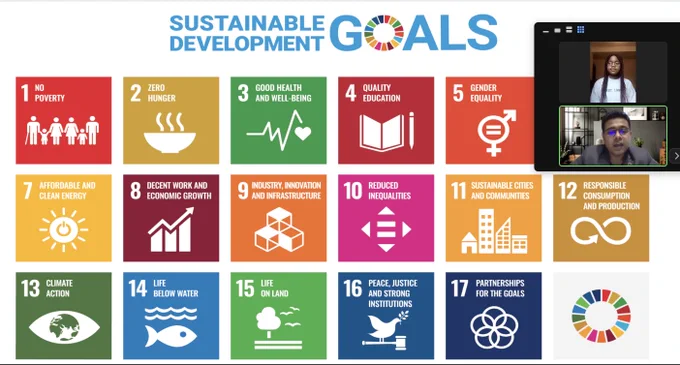 A screenshot of a Zoom meeting with a background showing the colored tiles with the numbered and labeled U.N. Sustainable Development Goals. In the upper right corner are the zoom squares of the two guest speakers in the middle of speaking with the students.