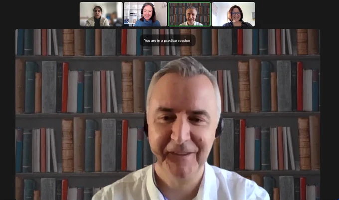 A screengrab of the webinar. Stuart McCarthy-Thompson is in the main frame, while Adeeba, Gemma and Nicola can be seen in a row across the top of the image. Stuart is smiling, wearing a headset and sitting in front of shelves of colourful books.