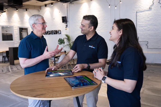 Tim is speaking with the founders of Hitwicket. They are surrounding a high top table that is holding two iPad Pros.