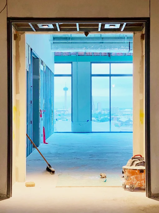 Reception area exiting the lobby elevators in which visitors will be met with terrazzo flooring, a plaster barrel vault ceiling, brick veneer, walnut wood paneling, custom artwork and panoramic views of the Tower of the Americas. 