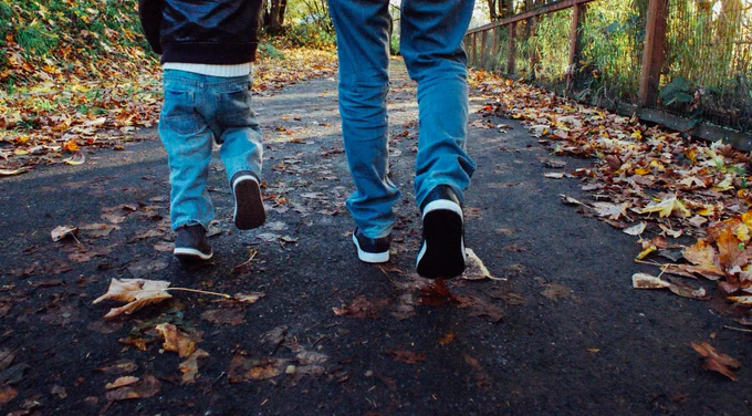 Child and adult walking in woods