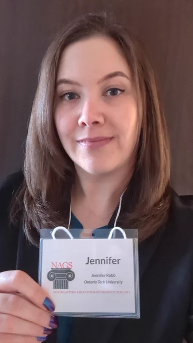 Jennifer Robb holding up her name badge from the NAGS annual meeting.