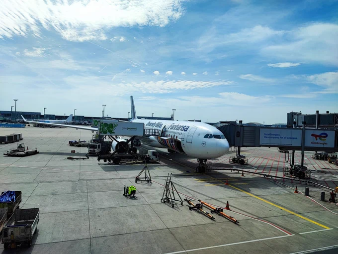 Airbus A330-300 at the gate. Instead of Lufthansa it has "Diversity Wins" and "Fanhansa" written on the side and some people from different cultures underneath. 