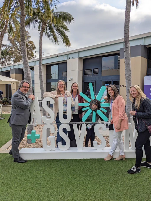 Five attendees alongside an ASU GSV  sign.