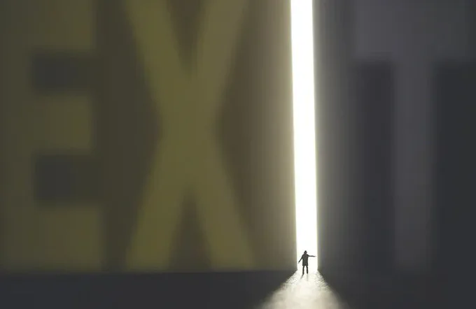 A large EXIT sign with a small figure exiting 