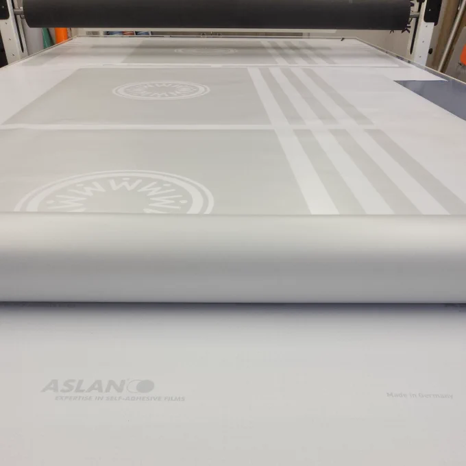 Some custom cut frosted vinyl being prepared on a workbench.