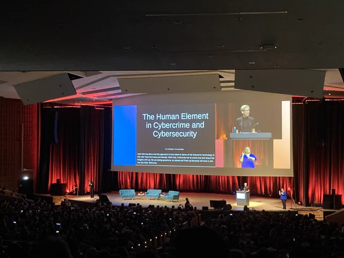 Wide view of keynote speaker with title slide in the background “the human element in cybercrime and cybersecurity”