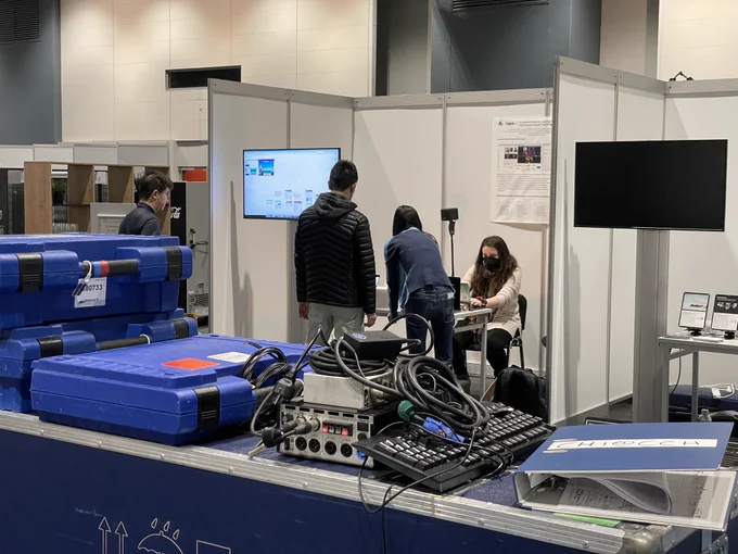 Three people in a their booth in the exhibition hall setting up a demo.