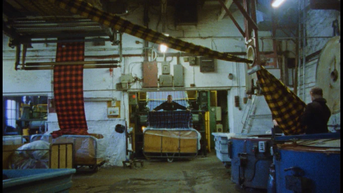 Workers operate machinery in a dyeing and finishing mill.