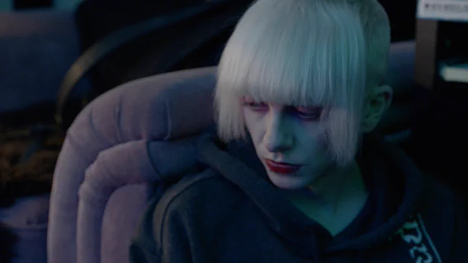 A person with a bleach-blonde fringe looks pensive. 