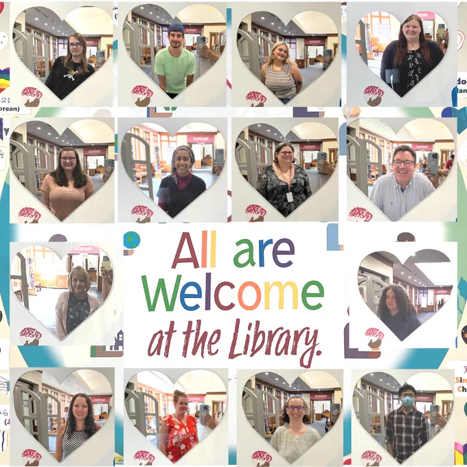 All are welcome at the library with heart shaped mirrors and different peoples faces in the mirrors.