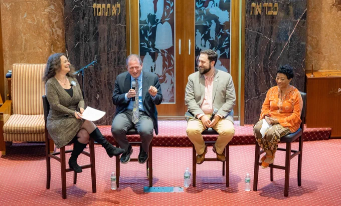 Panelists sit in a row of chairs. cc: Stella Dugall. 