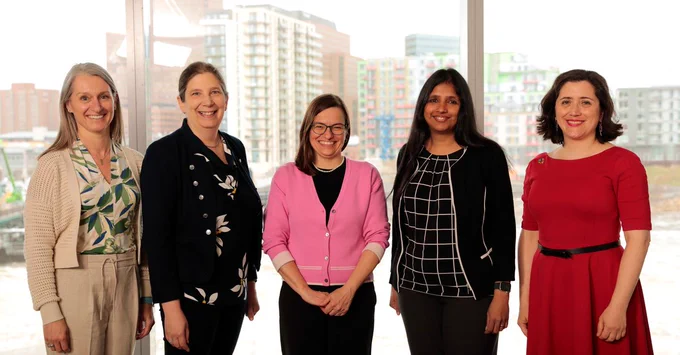 IMAGE: Portrait of the five chairholders of the NSERC Chairs for Women for Science and Engineering, smiling at the camera while standing in front of a large window providing a panoramic view of the city. 