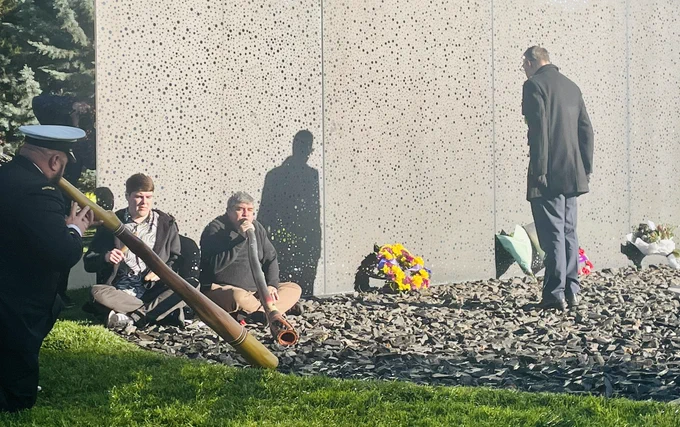 Me laying a wreath at the For Our country memorial with Didge and Yidaki players in foreground