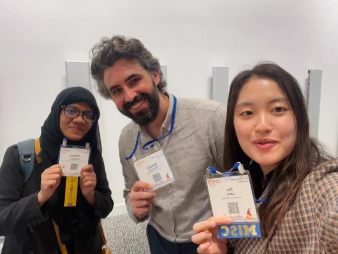 Three people taking a selfie while holding their CHI 2023 badges.