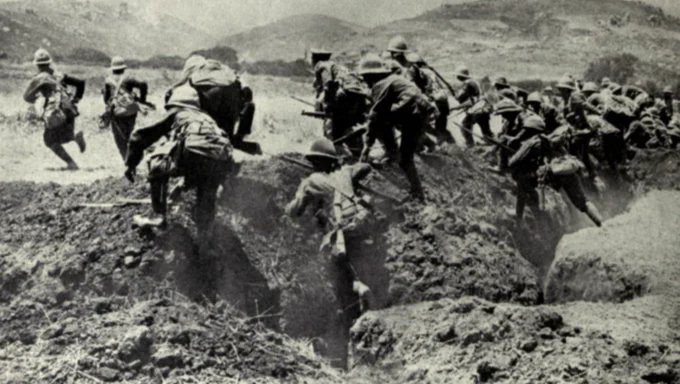 A black and white image of soldiers from Australia and New Zealand running from their trenches. 
