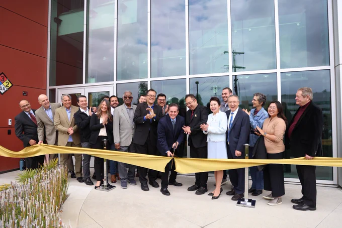 Person smiles and cuts a gold ribbon in front of Rongxiang Xu Bioscience Innovation Center